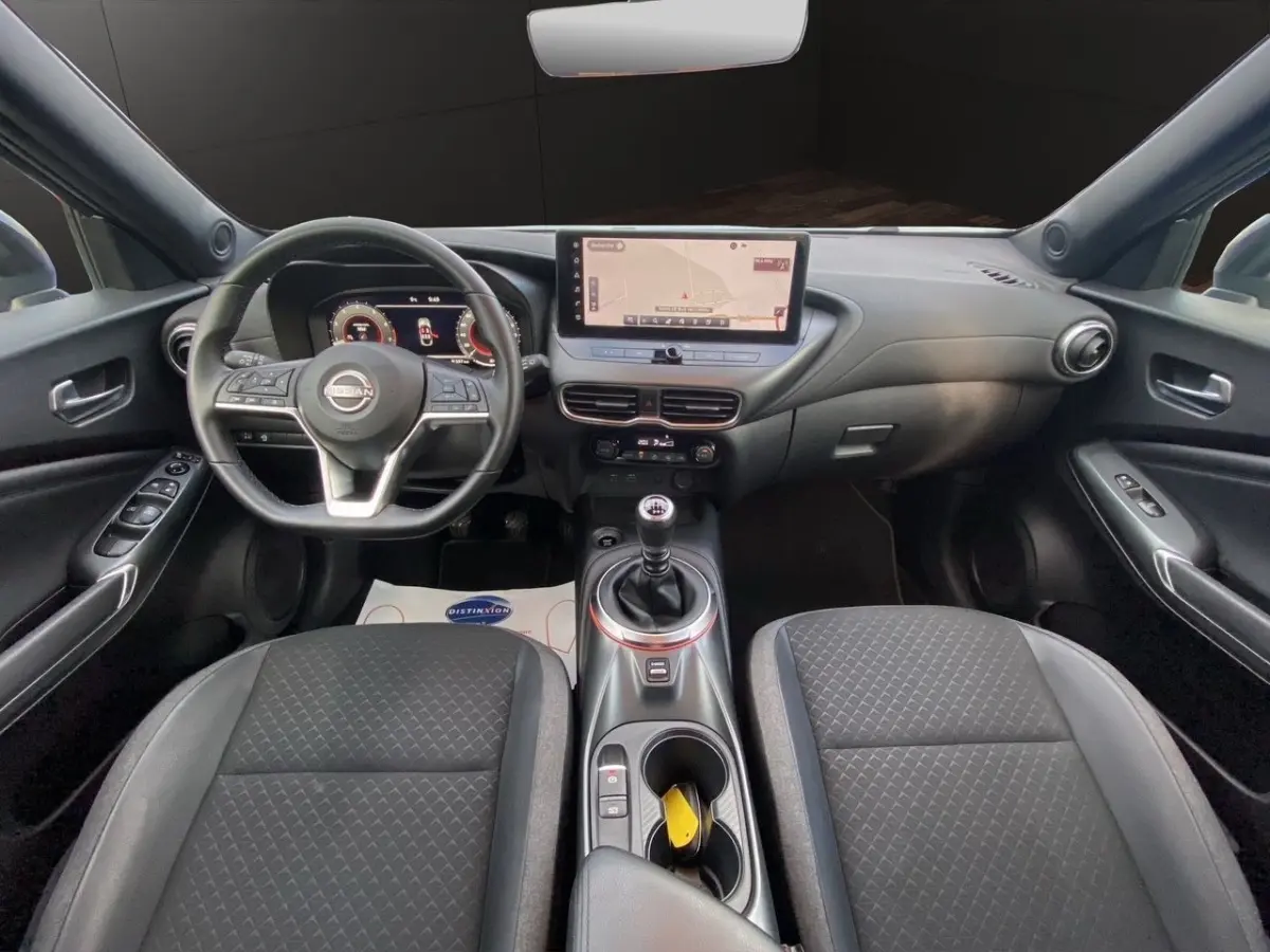 Vue intérieure avant du Nissan Juke 2025 avec tableau de bord noir, écran tactile central et volant multifonctions.