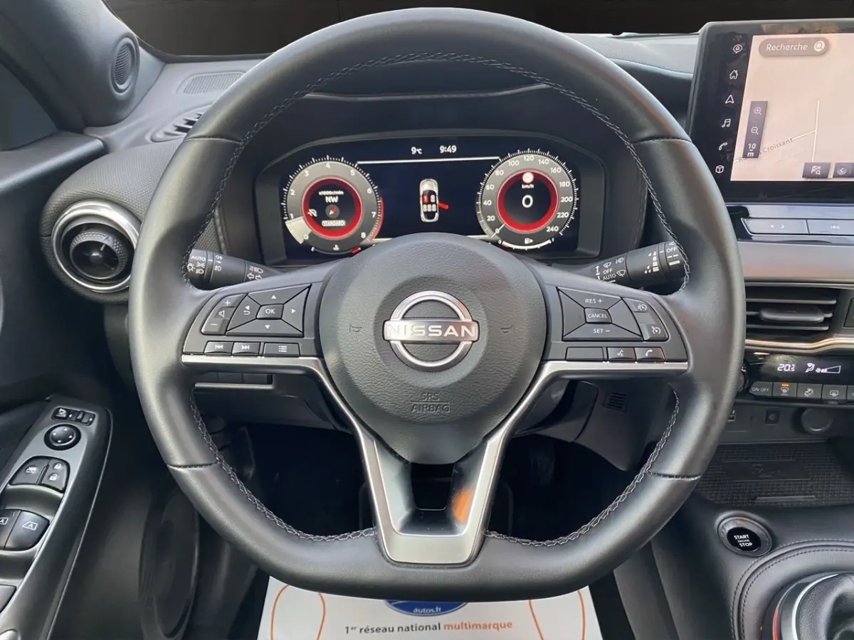 Vue intérieure centrée sur le volant cuir et alu du Nissan Juke 2025 avec tableau de bord numérique et écran tactile.