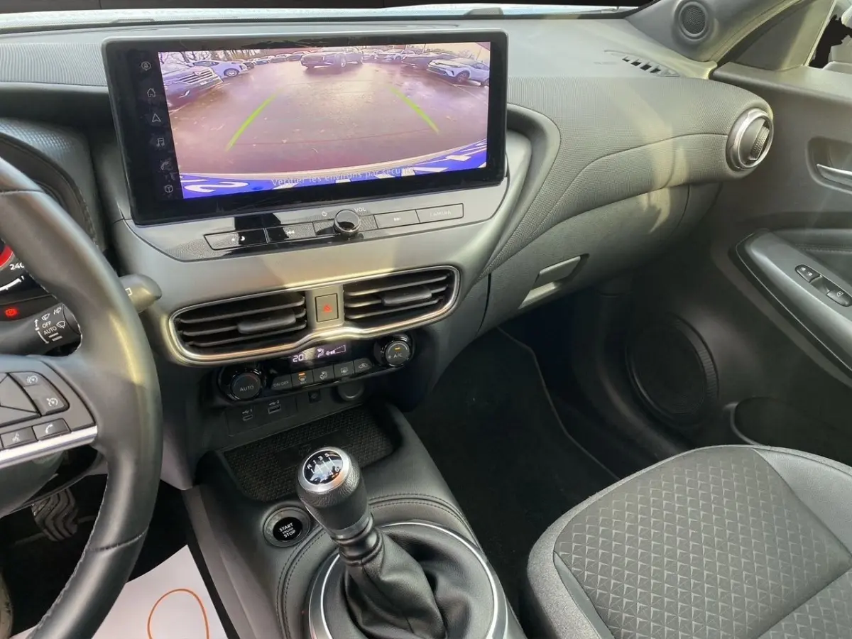 Vue intérieure côté conducteur du tableau de bord et écran tactile affichant la caméra de recul du Nissan Juke 2025.