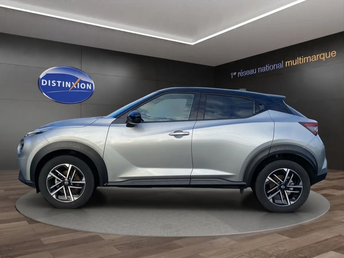 Vue de profil côté gauche d'un Nissan Juke gris clair avec jantes alliage et arches de roues noires.