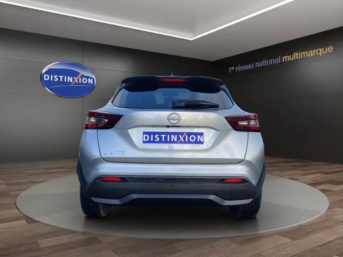 Vue arrière d'un Nissan Juke gris clair 2025, avec feux LED et logo Nissan bien visibles en showroom.