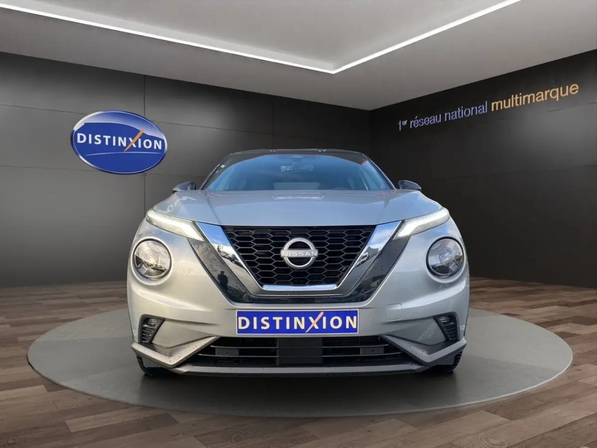 Vue frontale d'un Nissan Juke gris clair 2025 avec calandre noire et logo Nissan bien visible.
