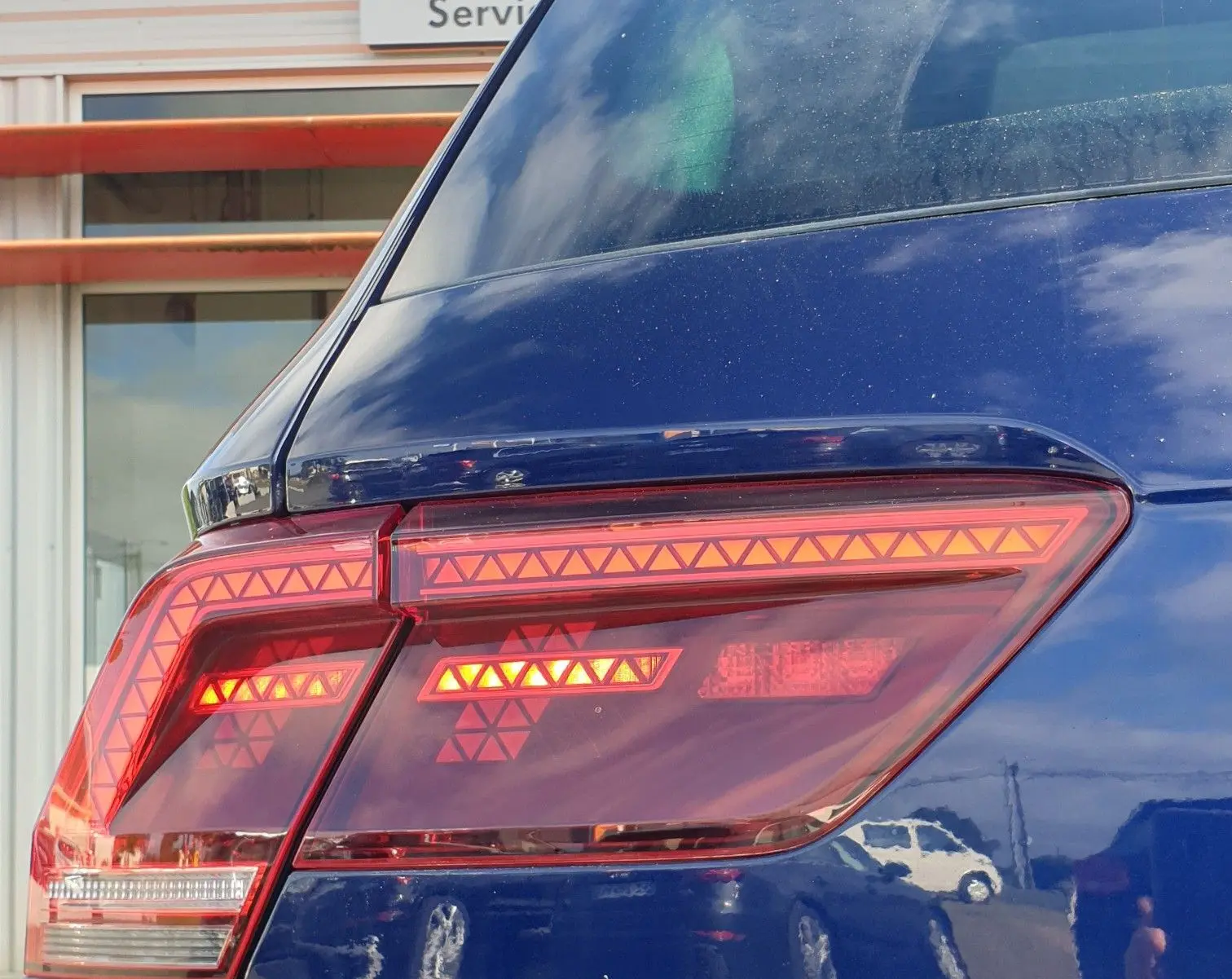 Gros plan sur le feu arrière droit d'un Volkswagen Tiguan bleu Atlantique métallisé, avec le logo Tiguan visible.
