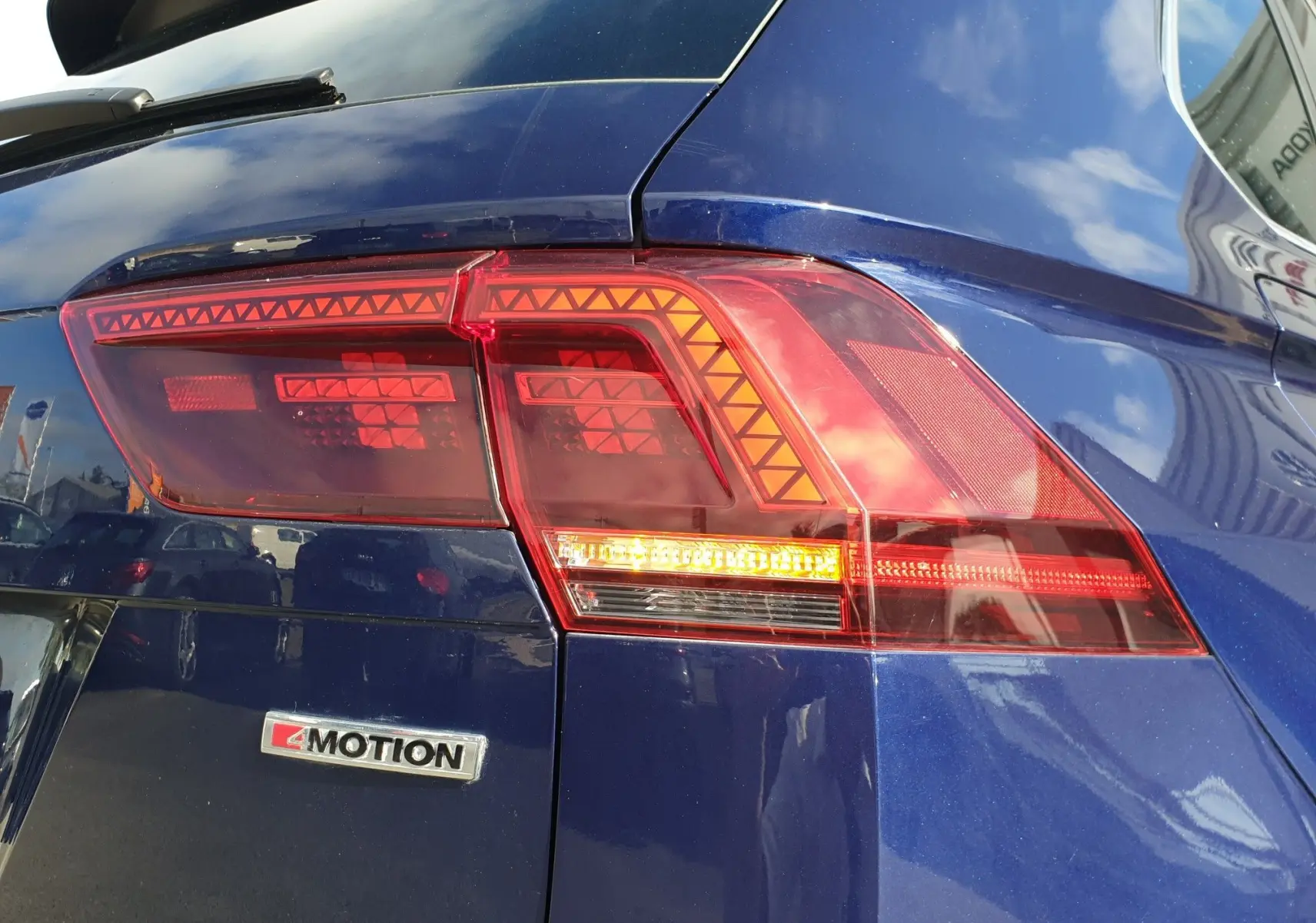 Gros plan sur le feu arrière droit et l'emblème 4Motion d'un Volkswagen Tiguan bleu Atlantique métallisé.