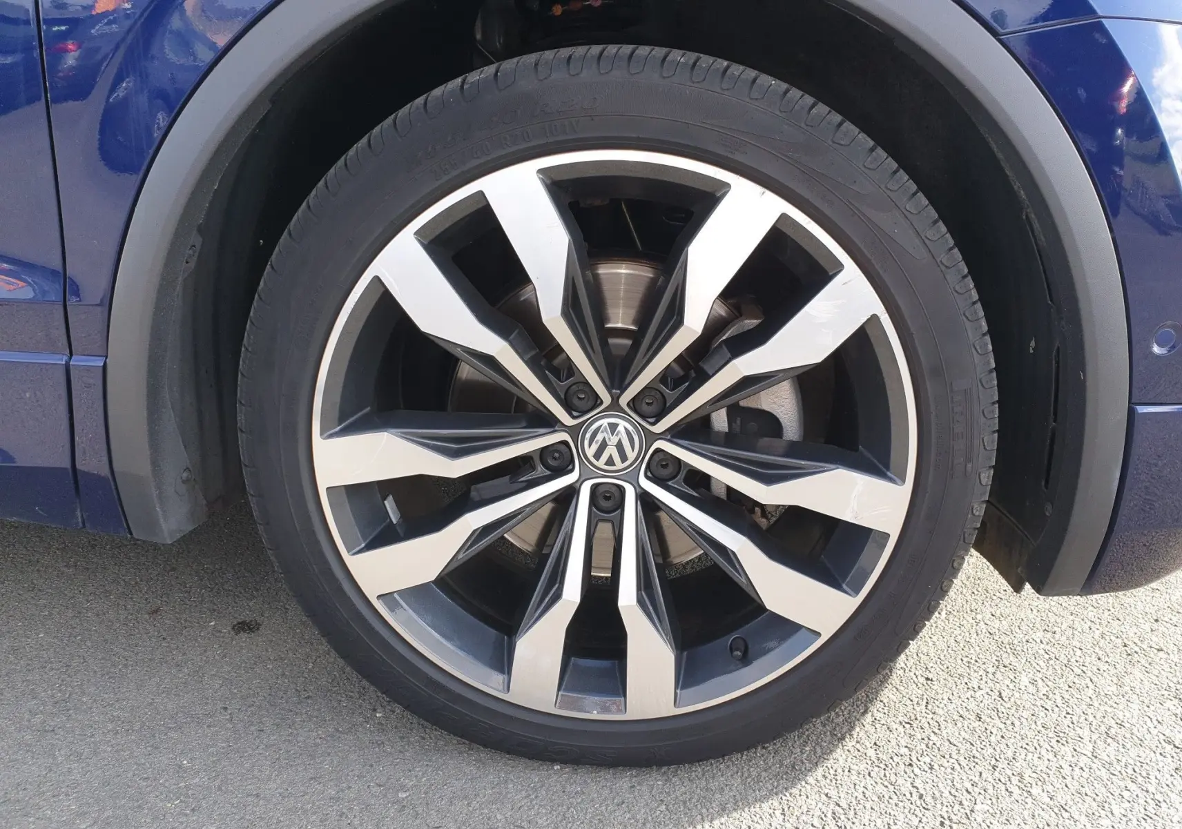 Gros plan sur la roue avant droite du Volkswagen Tiguan bleu Atlantique métallisé avec jante alliage 20 pouces au design moderne.