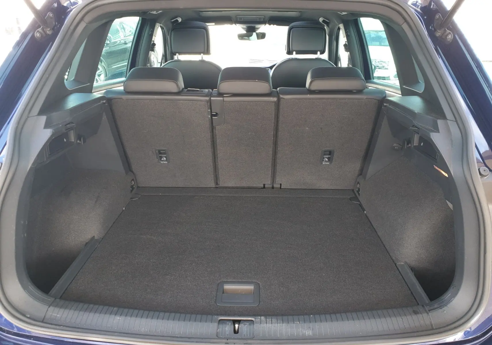 Vue arrière du coffre spacieux d'un Volkswagen Tiguan bleu Atlantique métallisé avec sièges arrière relevés.