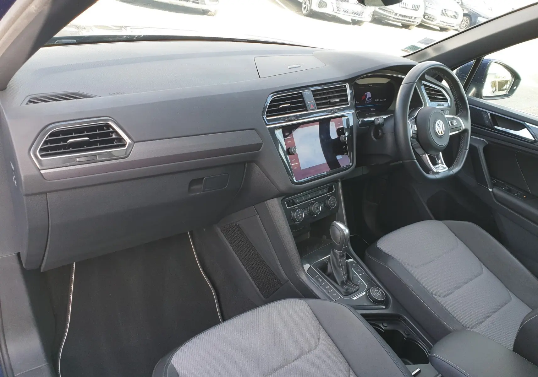 Vue intérieure côté conducteur droit du Volkswagen Tiguan 2018 avec tableau de bord moderne et console centrale équipée.