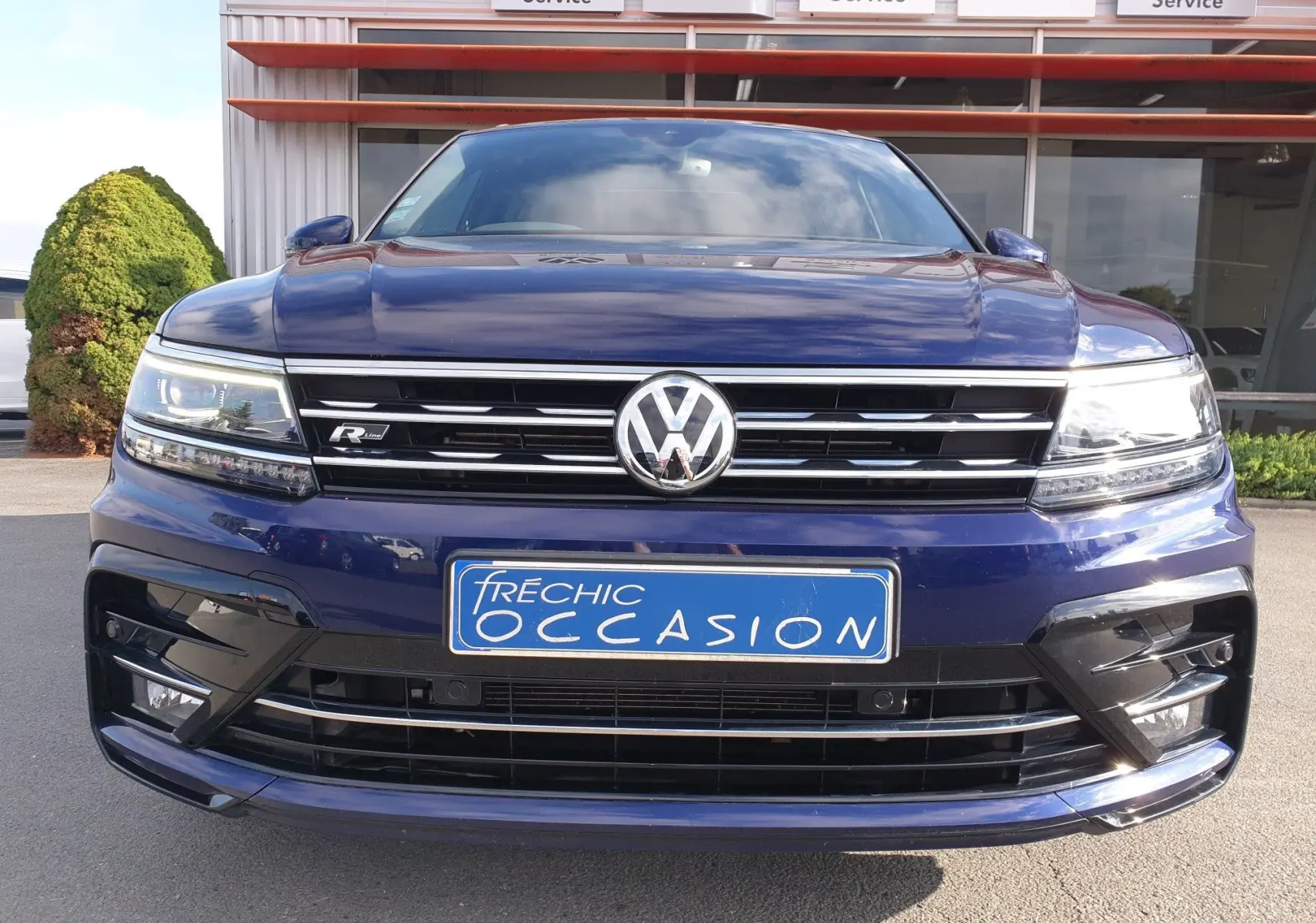 Vue frontale d'un Volkswagen Tiguan bleu Atlantique métallisé avec calandre R-Line et plaque d'occasion bleue.