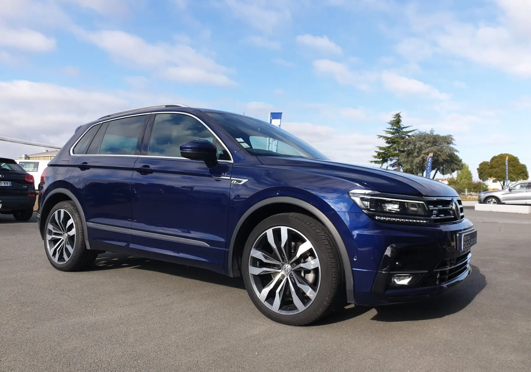 Volkswagen Tiguan bleu Atlantique métallisé en 3/4 avant droit, avec jantes alliage et calandre distinctive.