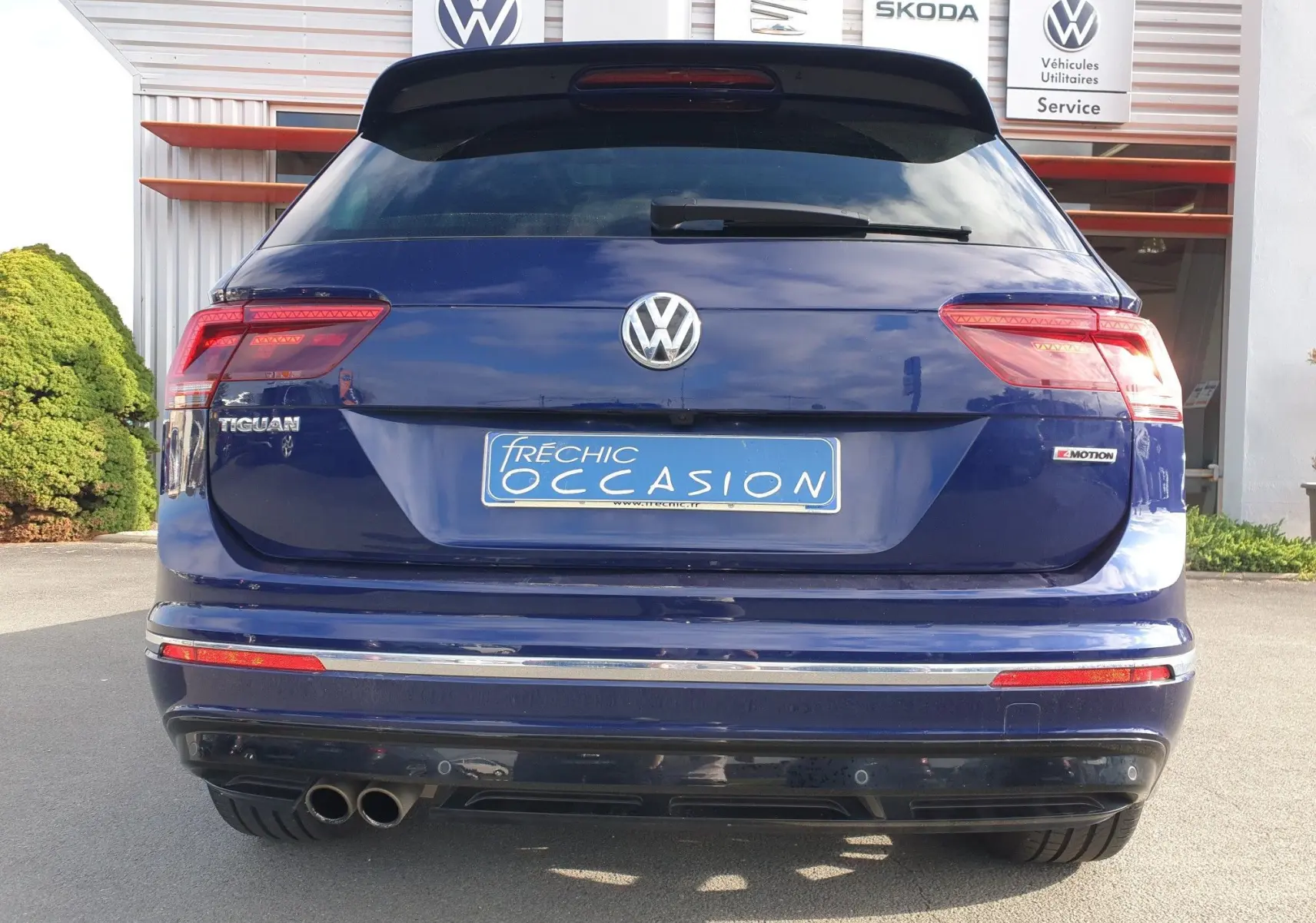 Vue arrière d'un Volkswagen Tiguan bleu Atlantique métallisé avec double sortie d'échappement et badge 4Motion visible.