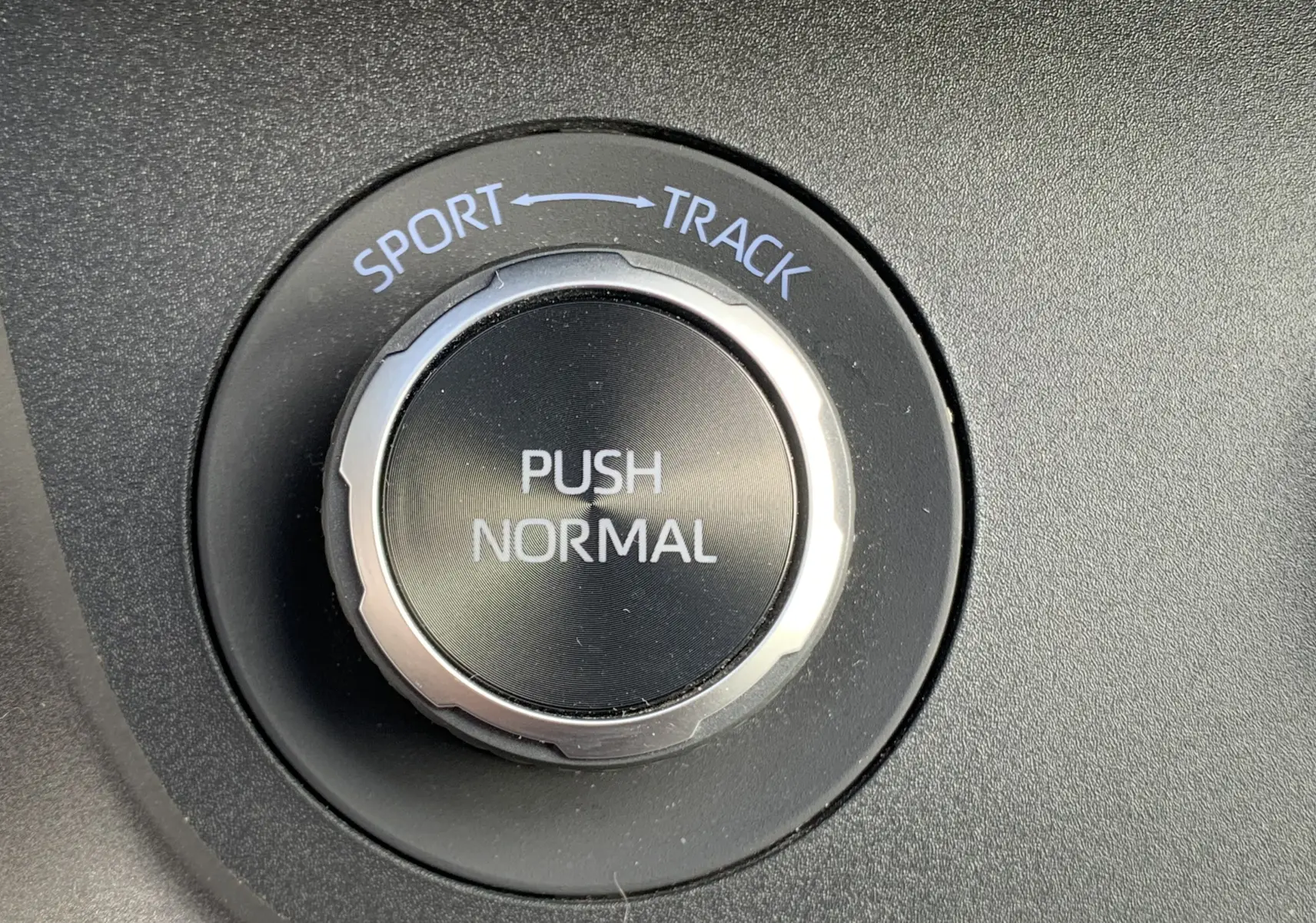Gros plan sur le sélecteur de mode de conduite noir avec options Sport, Normal et Track dans une Toyota Yaris blanche.