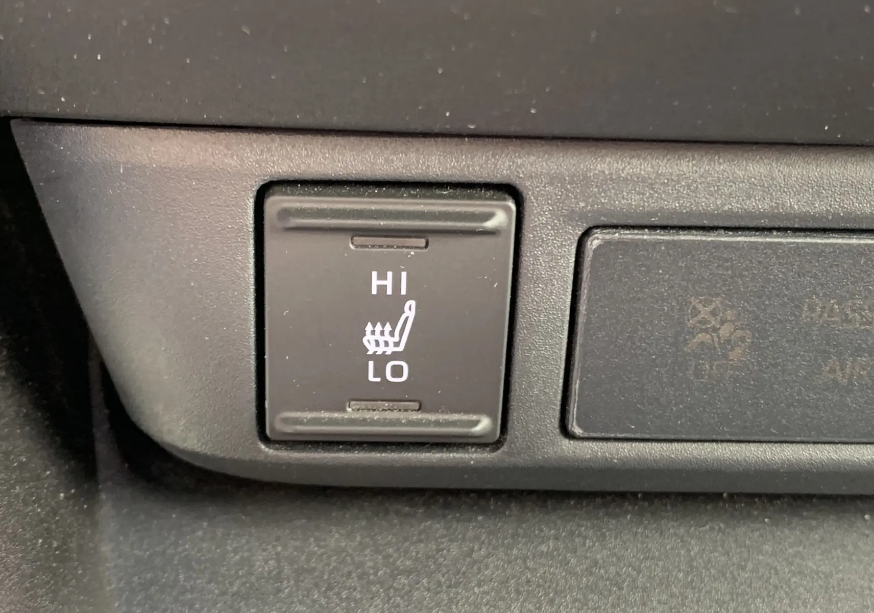 Gros plan sur le bouton de réglage de chauffage de siège avec options Hi et Lo dans une Toyota Yaris blanche.