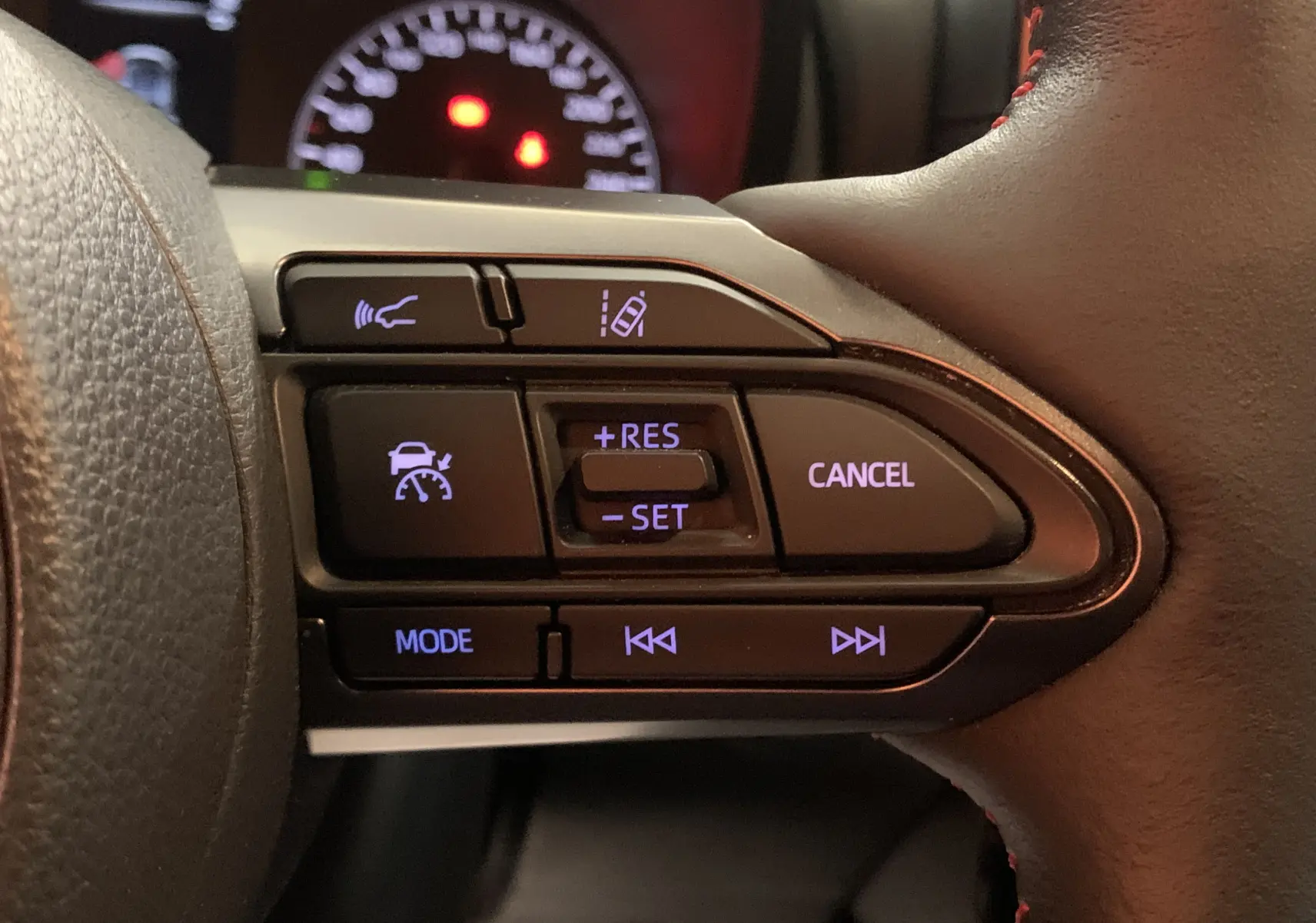 Détail des commandes au volant avec boutons de régulateur et assistance, Toyota Yaris 2021 intérieur cuir noir.