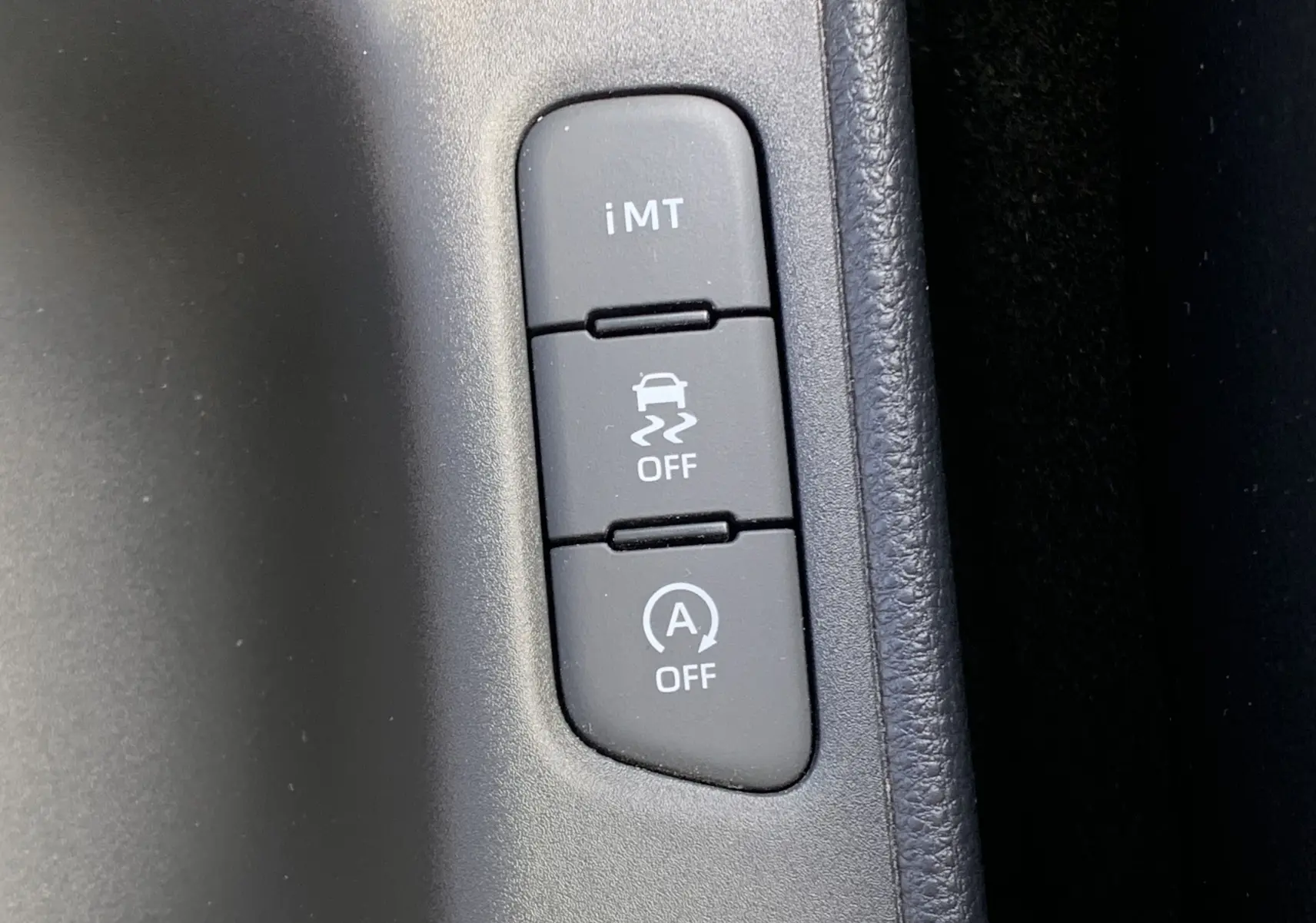 Boutons de contrôle du système iMT, de l'ESP et du stop-start sur la console centrale d'une Toyota Yaris blanche.