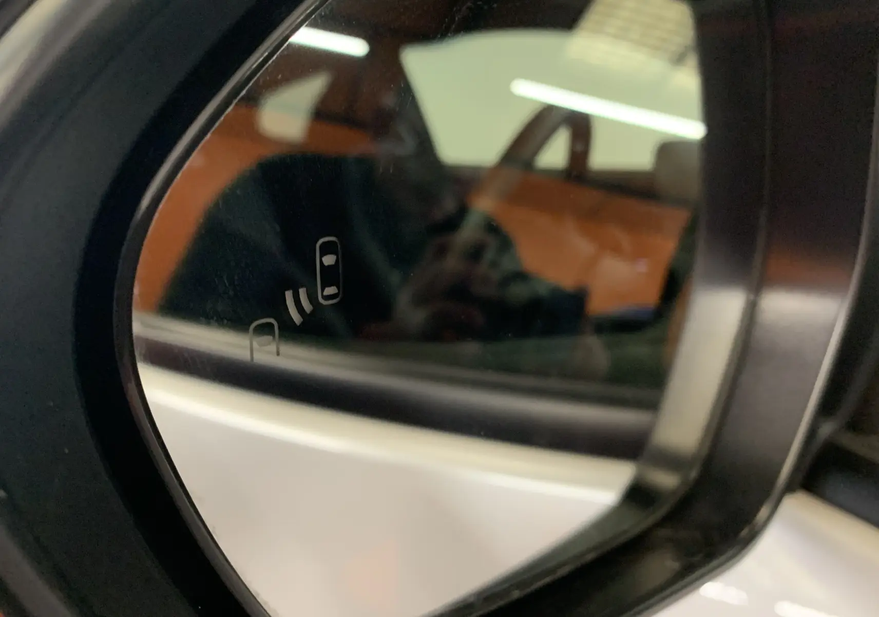 Rétroviseur côté gauche de la Toyota Yaris blanc métal 2021 avec indicateur d'angle mort intégré visible.