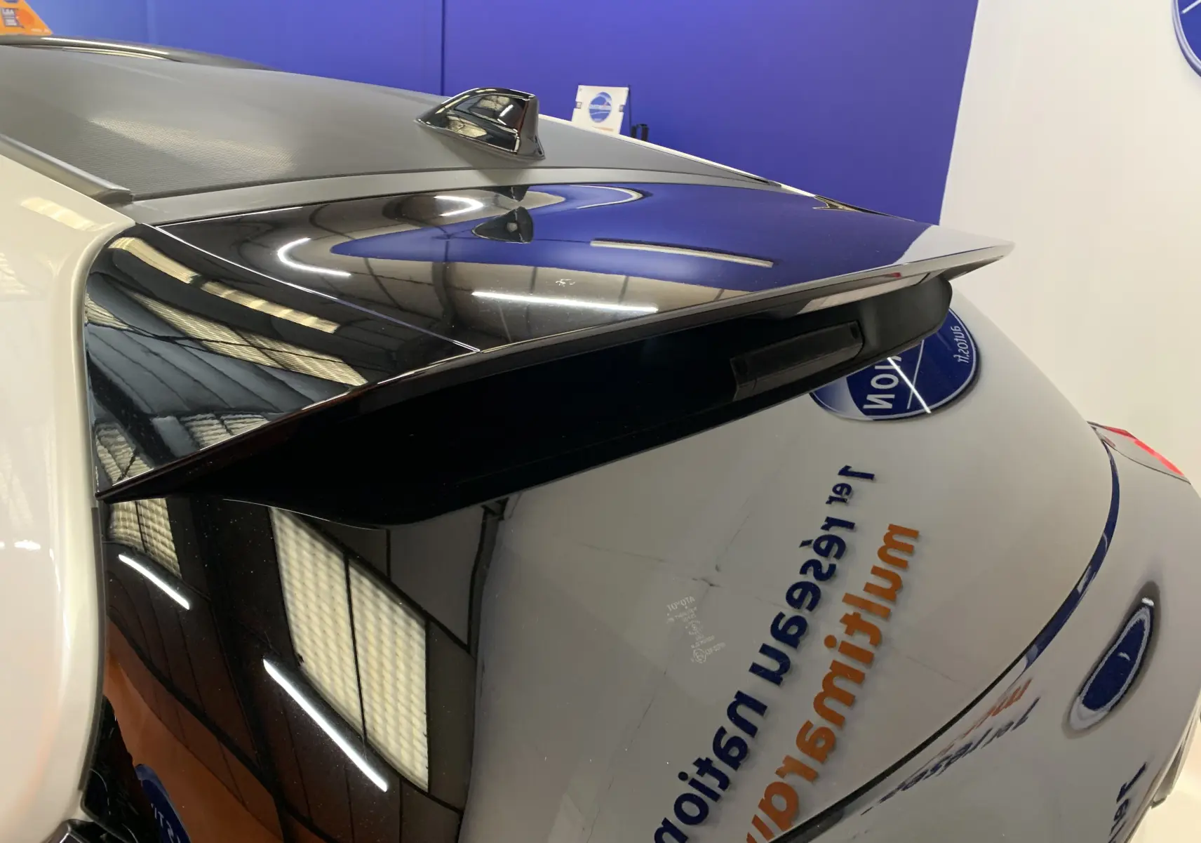 Vue arrière en gros plan de la Toyota Yaris blanc métal avec toit noir brillant et aileron sportif.