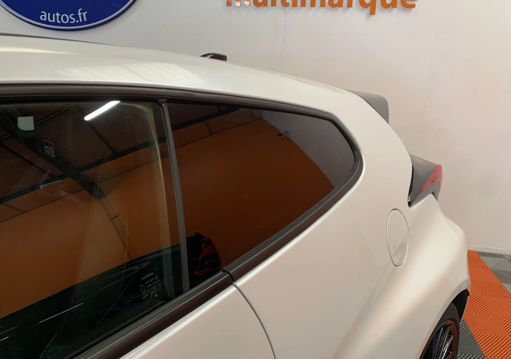 Vue latérale arrière droite de la Toyota Yaris 1.6 VVT-I 261 Premium GR blanc métal avec jantes sport et vitres teintées.