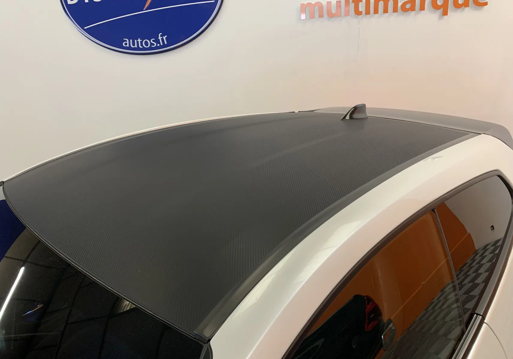 Toit noir texturé en carbone sur Toyota Yaris blanc métal, vue plongeante côté gauche arrière.