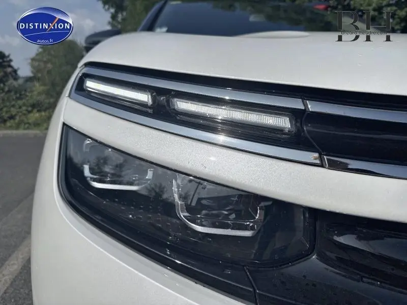Gros plan sur le phare avant gauche du Citroën C5 Aircross blanc nacré avec éclairage LED et détails chromés.