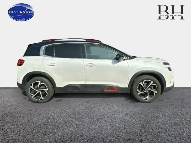 Profil droit d'un Citroën C5 Aircross blanc nacré avec toit noir et jantes alliage, souligné d'un insert rouge sur bas de caisse.