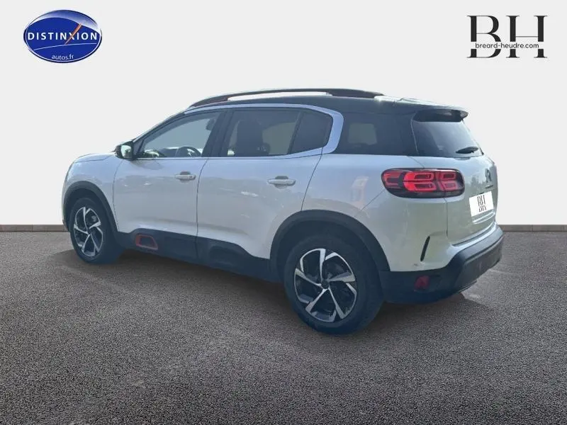 Vue 3/4 arrière droite d'un Citroën C5 Aircross blanc nacré avec jantes alu et attelage visible.