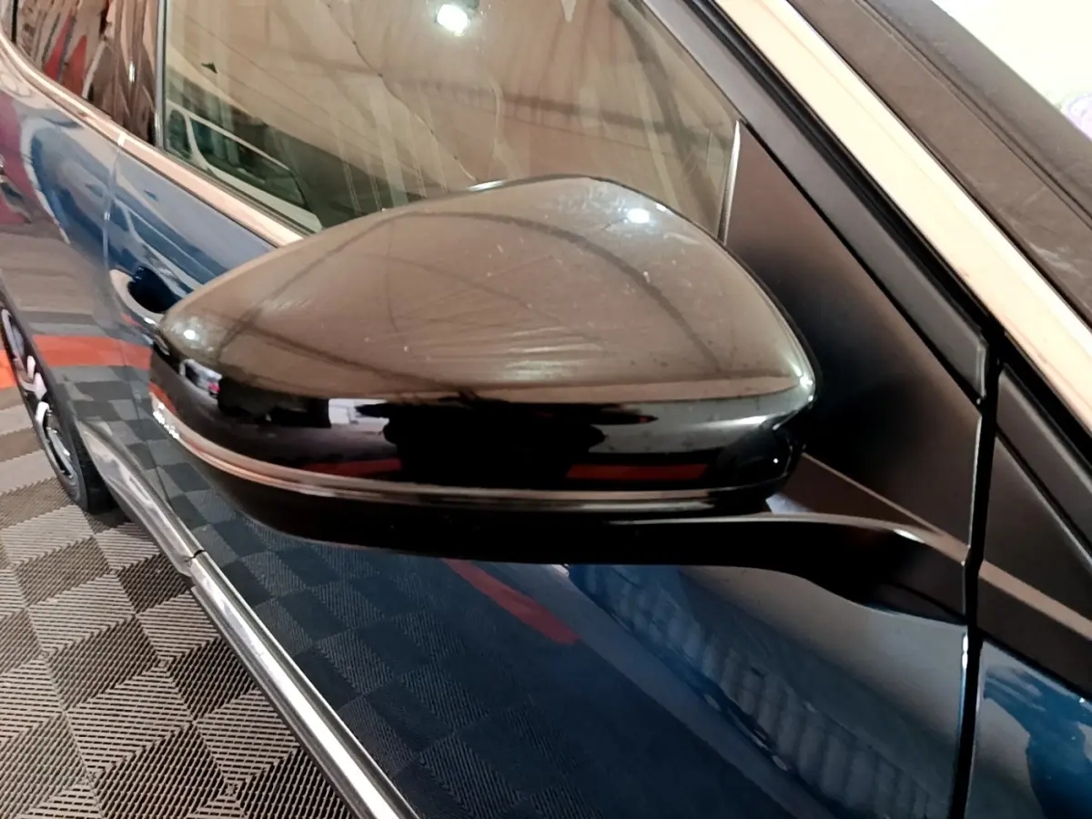Gros plan sur le rétroviseur noir côté gauche d’un Peugeot 3008 bleu, avec reflet sur la carrosserie.