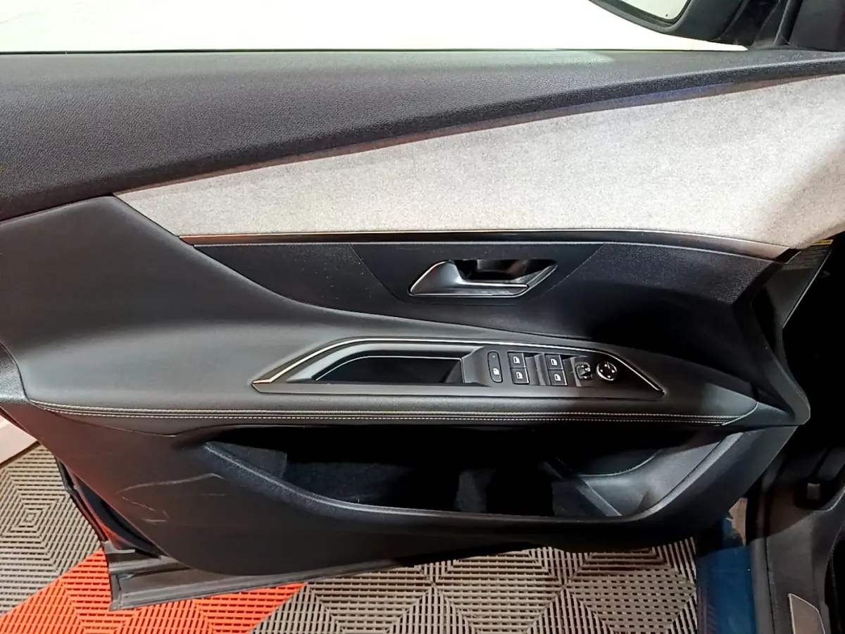 Vue intérieure de la porte côté conducteur du Peugeot 3008 bleu, avec commandes des vitres et poignée intégrée.