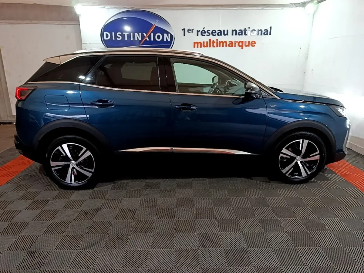 Vue latérale droite d’un Peugeot 3008 bleu 2021 GT avec toit noir et jantes alliage bicolores.