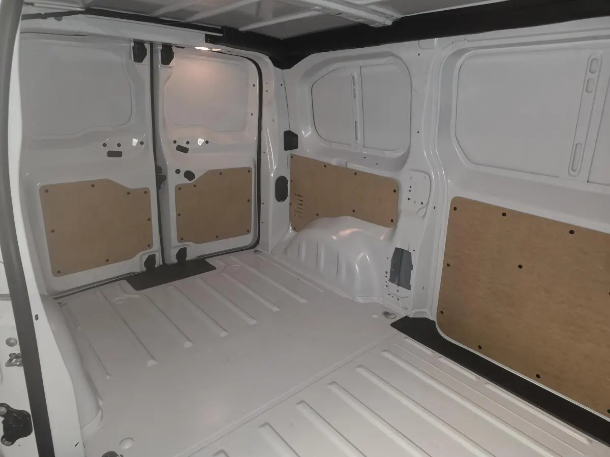 Vue intérieure arrière du fourgon Opel Vivaro blanc 2025, montrant l'espace de chargement avec panneaux de protection en bois.