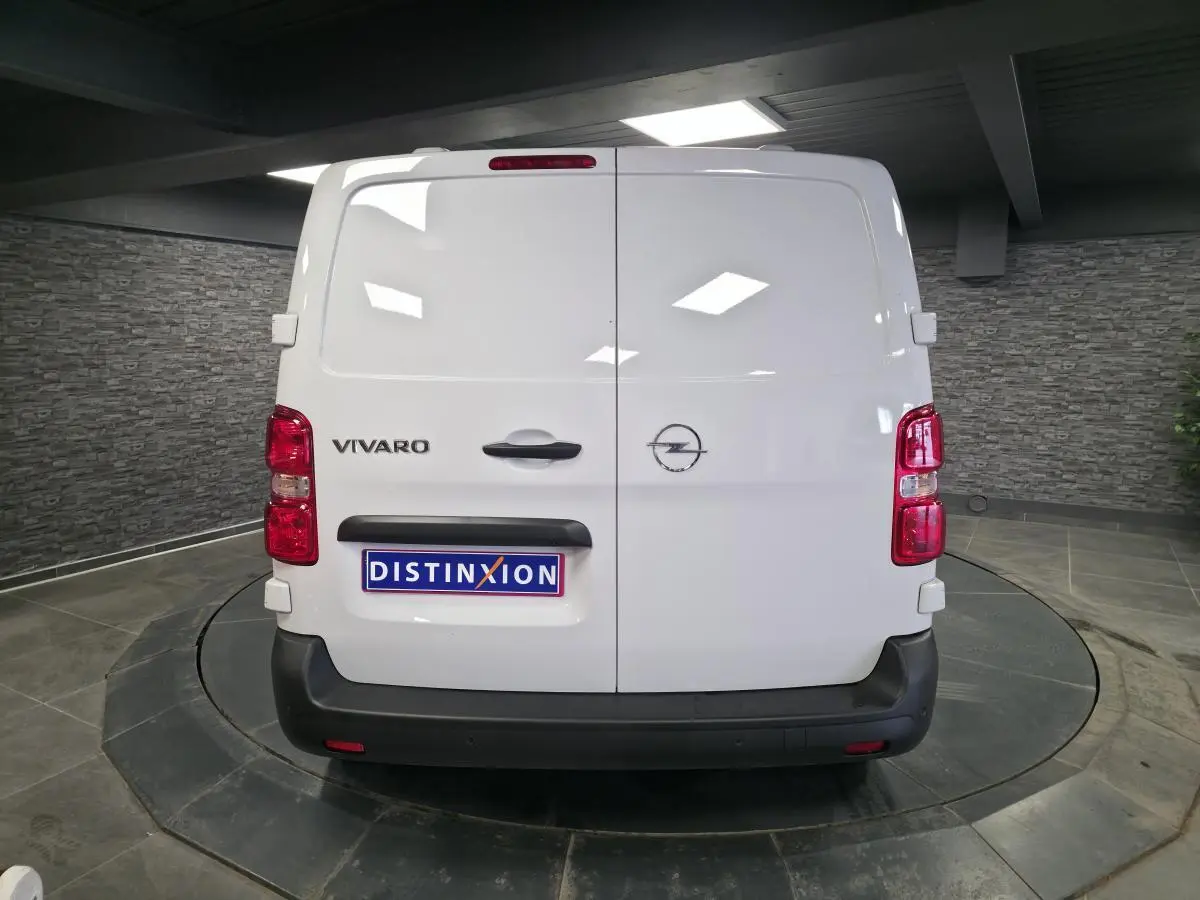 Vue arrière d'un Opel Vivaro blanc avec portes battantes et pare-chocs noirs dans un showroom.