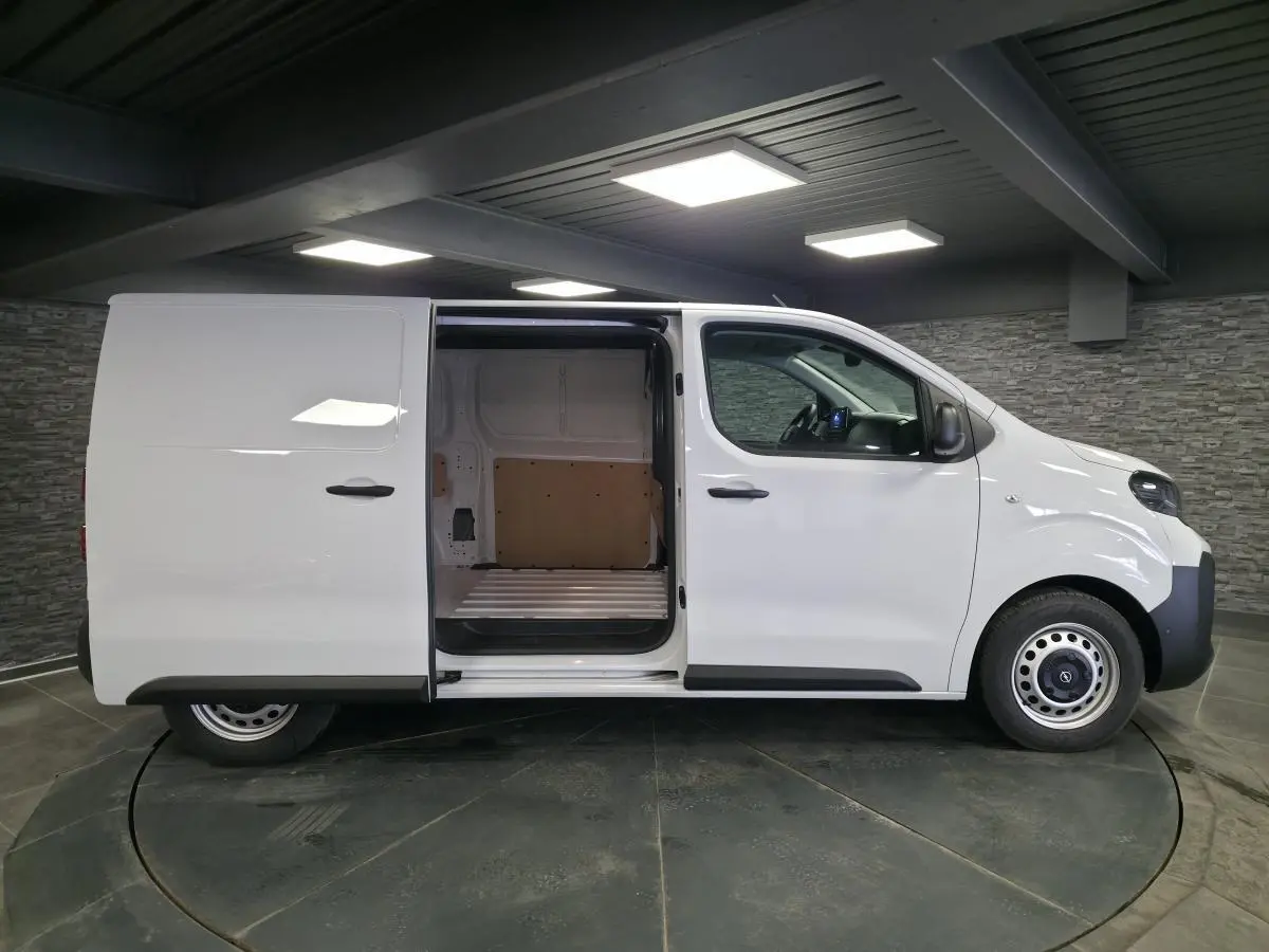 Vue latérale droite d’un Opel Vivaro blanc 2025 avec porte coulissante ouverte dévoilant l’espace de chargement vide.