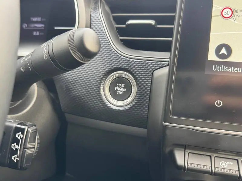 Détail intérieur du tableau de bord du Renault Arkana 2025 montrant le bouton Start Engine Stop et la texture noire autour.