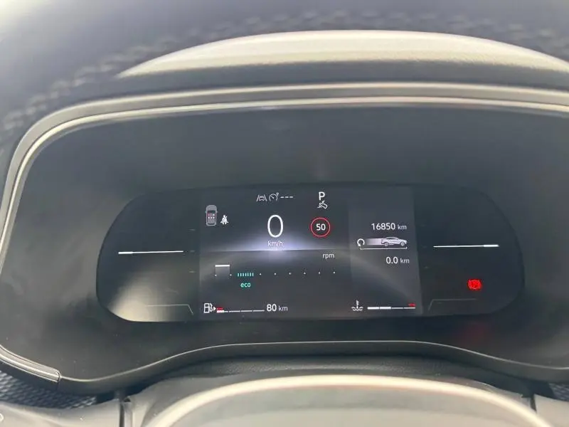 Tableau de bord numérique de Renault Arkana 2025, affichage de vitesse, autonomie et alertes, vue frontale rapprochée.