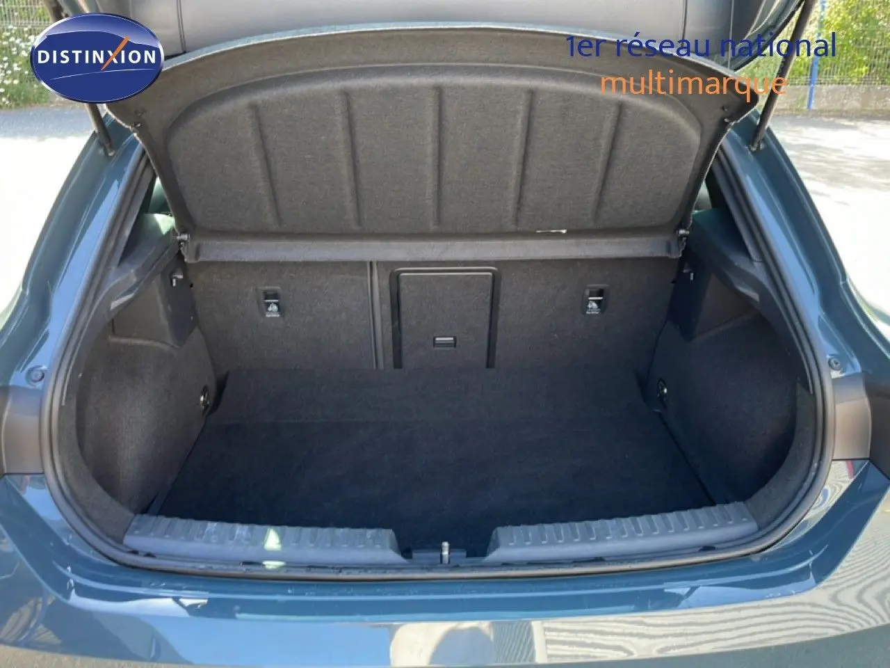 Coffre ouvert vu de l'arrière d'une CUPRA Leon 1.5 eTSI 150CH DSG bleu Fjord, montrant un espace de chargement propre et spacieux.