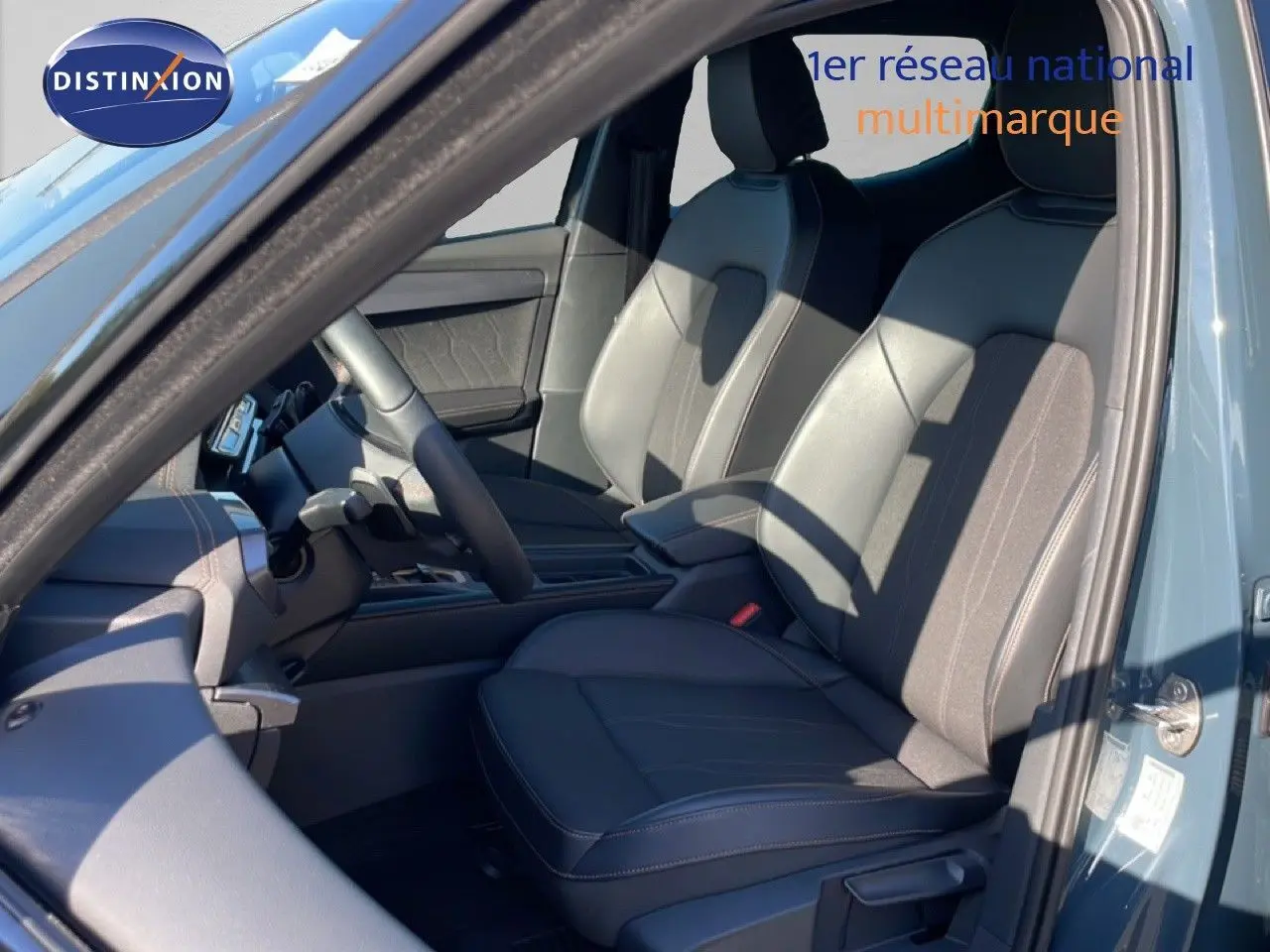 Vue intérieure côté gauche du CUPRA Leon 1.5 eTSI 150CH DSG bleu fjord, sièges avant en cuir noir et tissu.