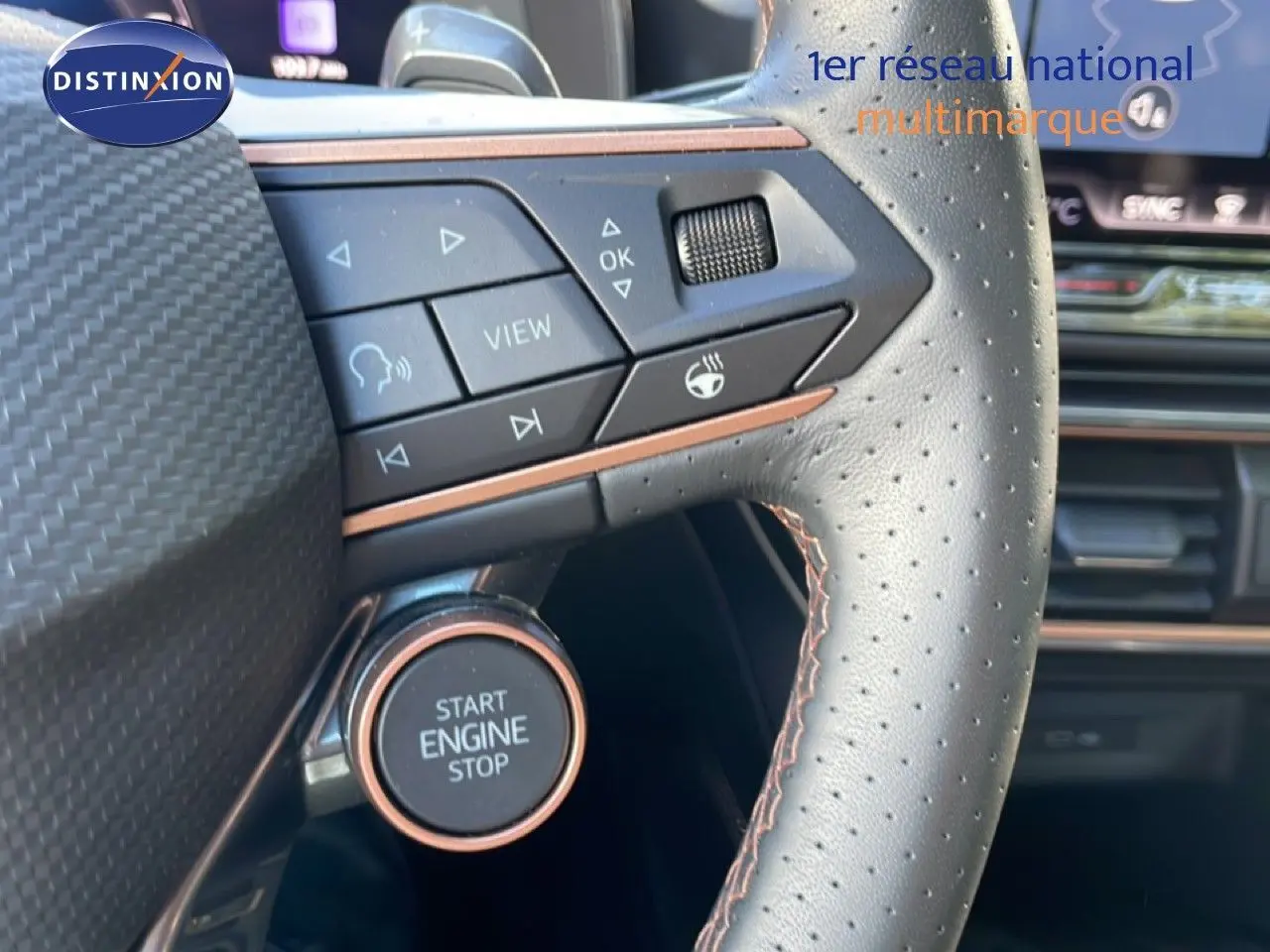 Gros plan sur le volant en cuir perforé de la CUPRA Leon bleu Fjord, avec bouton Start Engine Stop et commandes intégrées.