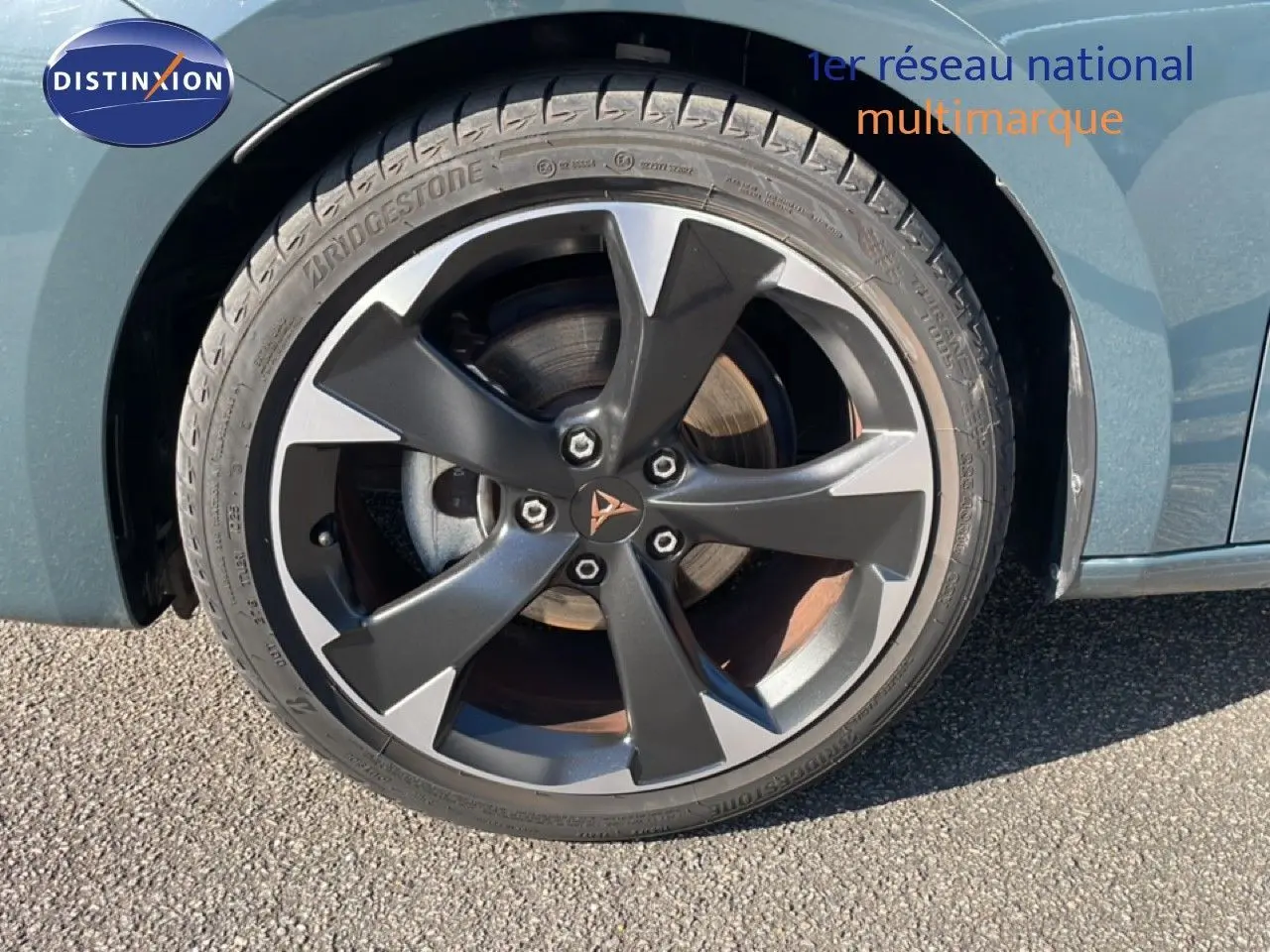 Gros plan sur la roue avant gauche d'une CUPRA Leon bleu Fjord avec jante alliage bicolore et logo CUPRA central.