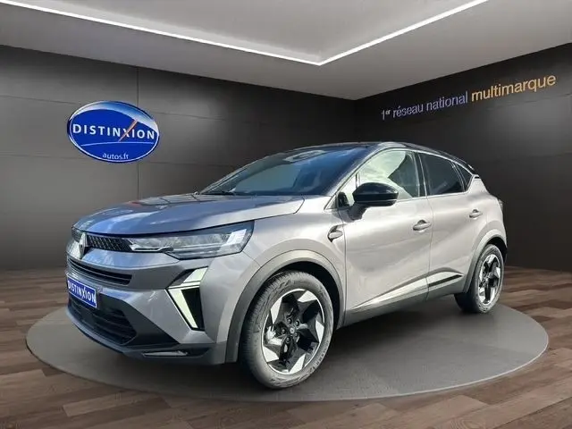 Renault Captur Techno full hybrid 2025 gris foncé, vue 3/4 avant droit, jantes noires et détails LED avant visibles.