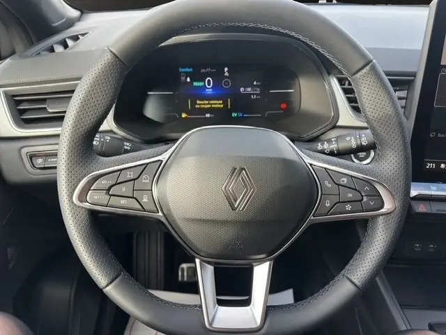 Vue rapprochée du volant en cuir perforé du Renault Captur gris foncé 2025 avec commandes multifonctions et affichage numérique.