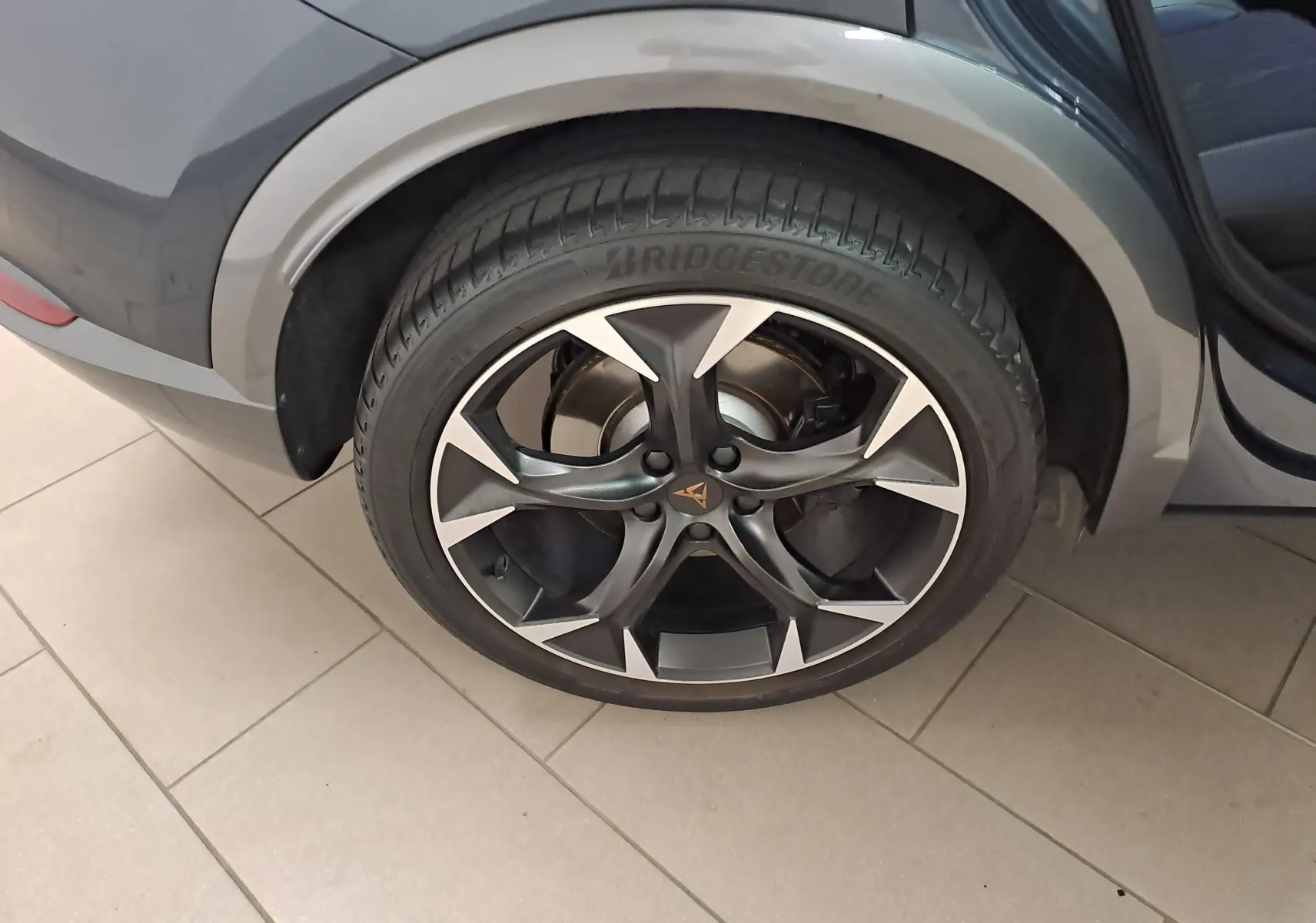 Gros plan sur la roue arrière droite du CUPRA Formentor gris magnétique, avec jante alliage noire et argentée au design sportif.