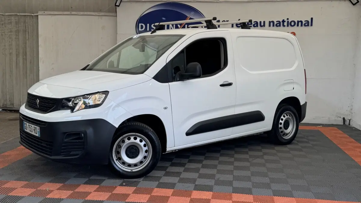 Vue 3/4 avant droit d'un utilitaire Peugeot Partner blanc avec barres de toit et jantes acier grises.