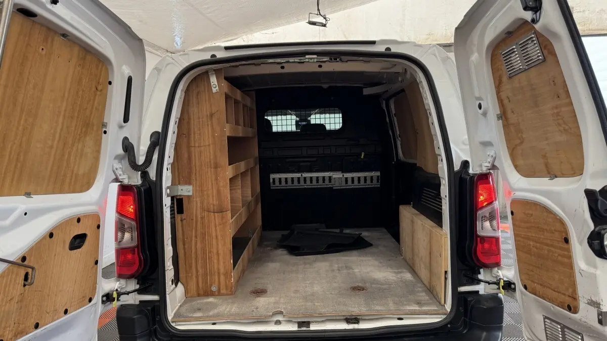 Vue arrière ouverte du Peugeot Partner blanc 2021 avec aménagements en bois dans l’espace de chargement.