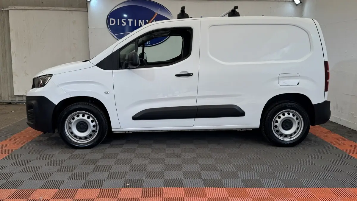 Vue de profil côté gauche d’un utilitaire Peugeot Partner blanc avec protections latérales noires et jantes acier.