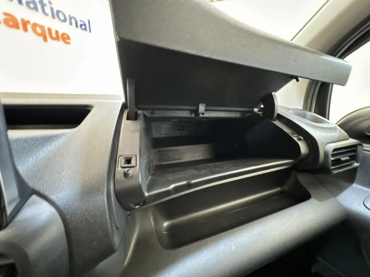 Gros plan sur la boîte à gants ouverte côté passager dans l’habitacle noir du Peugeot Partner blanc.