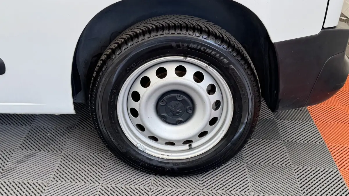 Gros plan sur la roue arrière droite en jante acier du Peugeot Partner blanc, avec pneu Michelin visible.