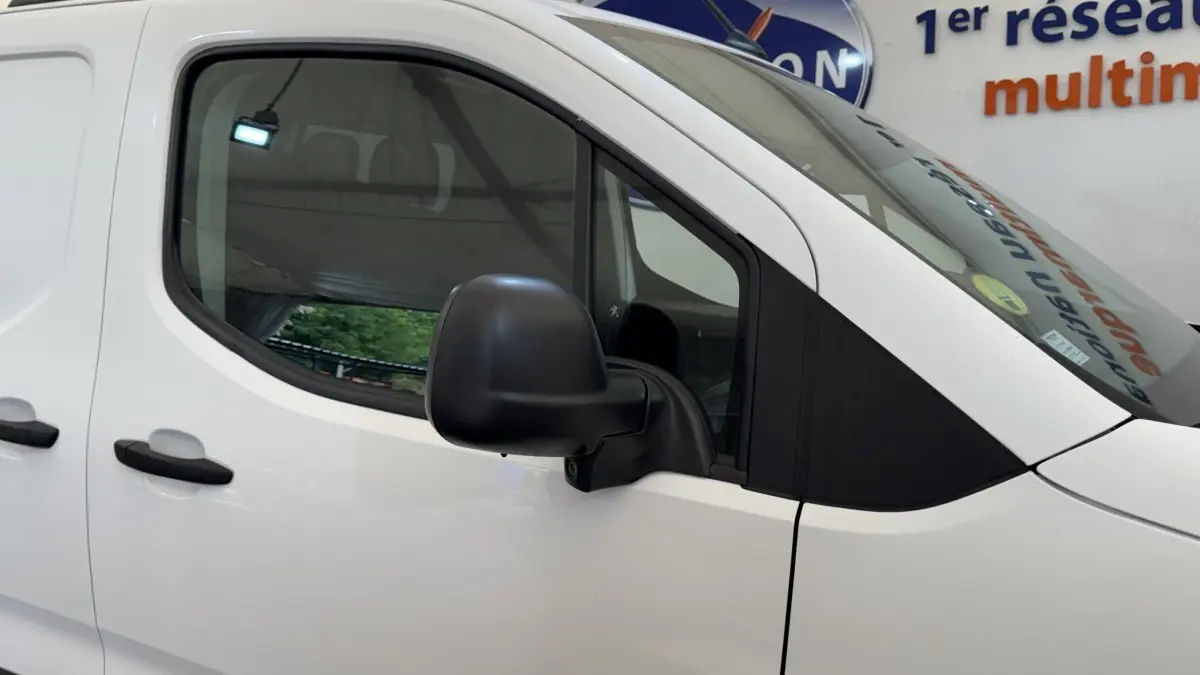 Vue latérale gauche rapprochée du Peugeot Partner blanc, mettant en valeur la portière et le rétroviseur noir.