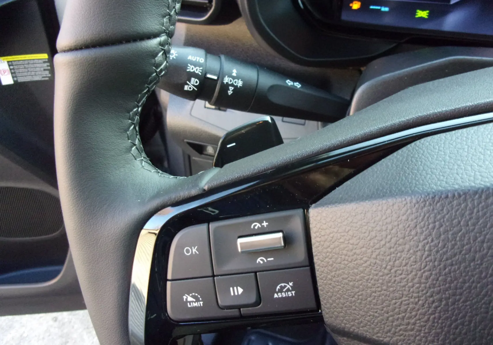 Gros plan sur la partie gauche du volant gris du Citroën Berlingo 2025 avec commandes de régulateur et tableau de bord numérique.