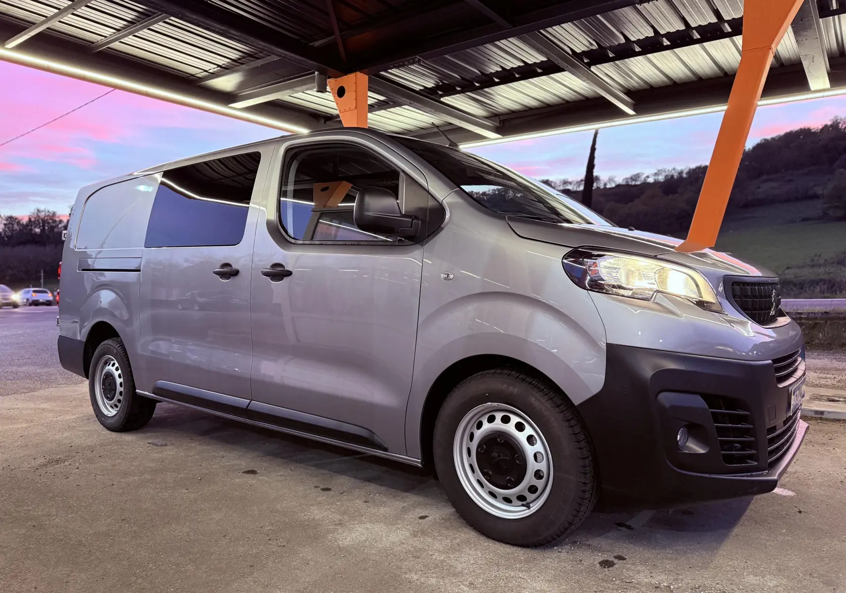 Peugeot Expert Cabine Approfondie gris Artense métal vu de profil côté gauche sous un abri au crépuscule.