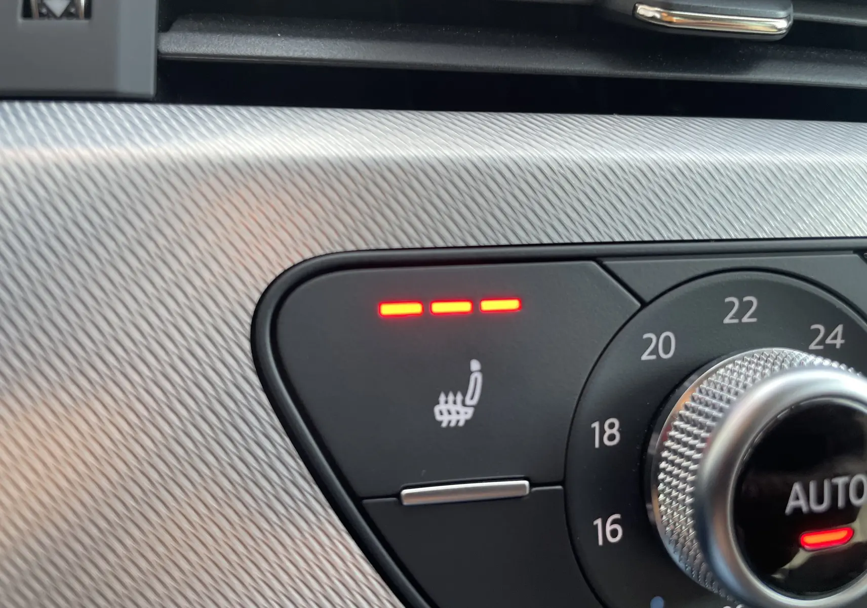 Gros plan sur le bouton de chauffage de siège actif et le réglage de la température intérieure d'une Audi A4 Avant blanche de 2022.