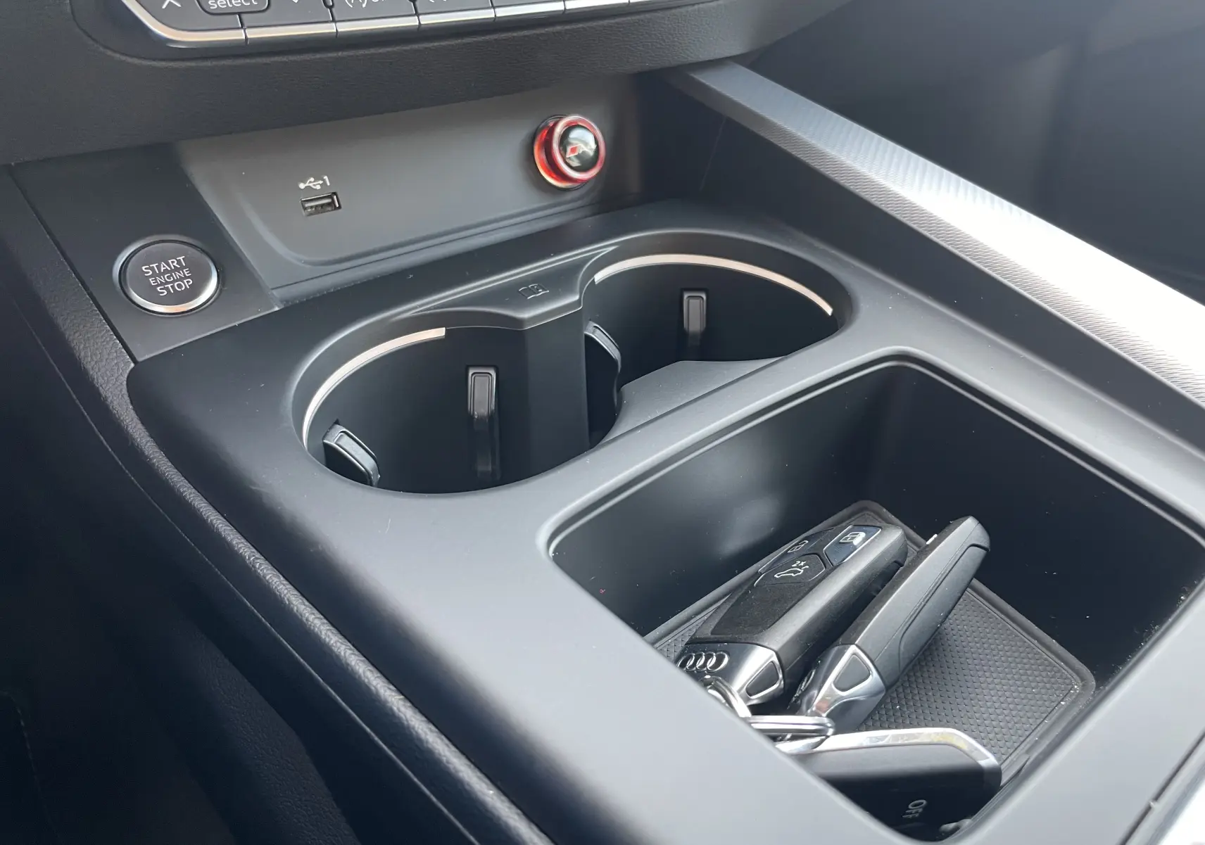 Gros plan sur la console centrale de l'Audi A4 Avant blanc 2022, avec clés, bouton Start et porte-gobelets visibles.